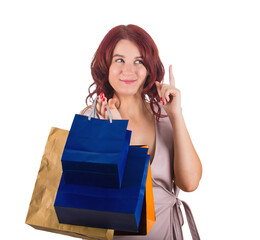 Redhead woman shopaholic trying to pay attention pointing forefinger up as has an idea. Looking thoughtful and sneaky female carrying shopping bags isolated on transparent background