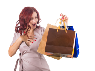 Surprised redhead woman keeps hand to chest while holding multiple shopping bags in her hand
