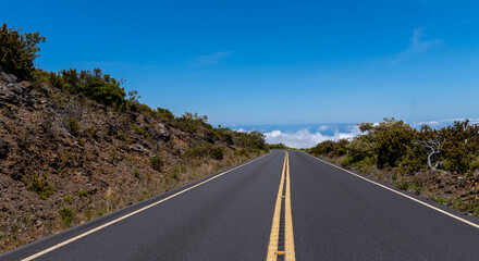 Scenic road winds through a mountainous landscape under a clear blue sky.