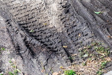 A detailed closeup image showcasing a tire track etched into the dirt