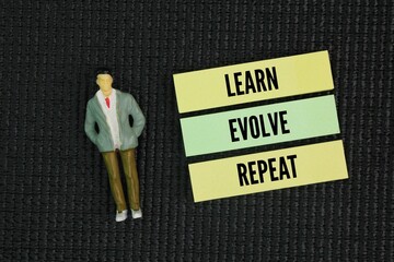 Miniature people and paper with inspirational and motivational words for success Learn, Evolve,...