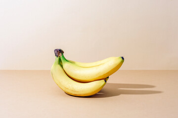 Fresh ripe bananas on beige background with sharp shadows. Closeup