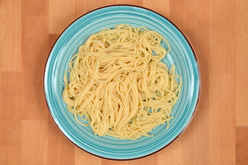 Cooked spaghetti served on a blue plate, photographed from a top-down angle