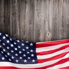 The United States flag draped along the bottom edge of a rustic wooden background. Stock photo.
