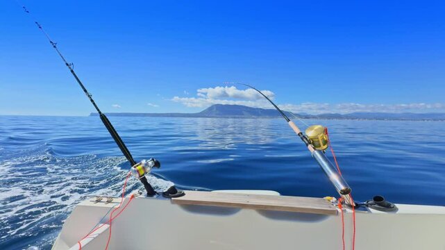 Sport boat trolling ocean with rods, reels, saltwater outboard fishing