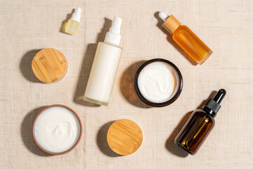 Obraz premium Overhead shot of skincare products including creams serums and lotions on a beige surface flat lay