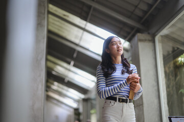 Young student walking in university corridor holding a book and looking up