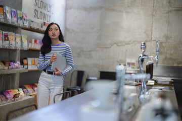 Coffee shop manager holding laptop and checking supplies standing at the counter