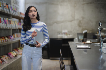 Entrepreneur holding laptop walking in her store looking away