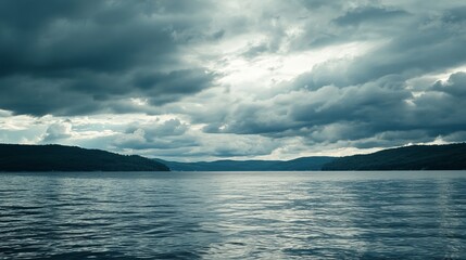 Dramatic cloudscape over a serene lake, with dark, brooding sky and calm water reflecting the light