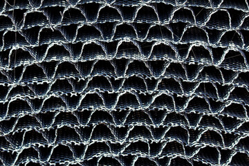 Detailed close-up of metal mesh fabric with a repeating wavy pattern, showing texture, structure,...