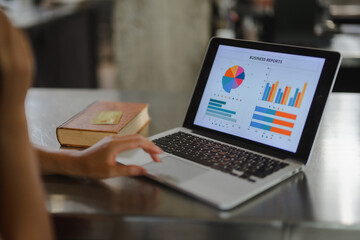 Businesswoman analyzing business reports on laptop with charts and graphs