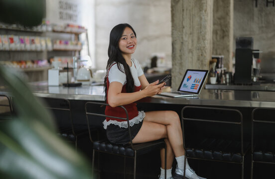 Asian businesswoman working remotely using laptop and smartphone in a cafe
