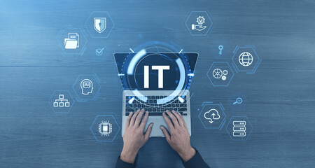 Hands typing on laptop with IT icons and technology symbols on blue background.