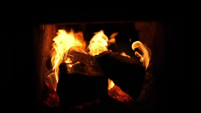 Close-up of burning firewood inside a stove. Intense flames, glowing embers, and crackling textures create a warm, rustic and cozy atmosphere. Natural indoor fire.