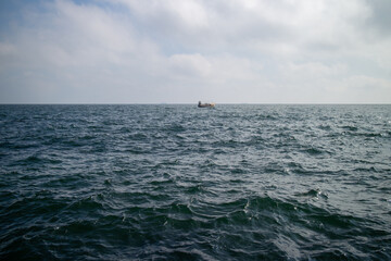 A solitary fishing boat is seen on the open waters of the Black Sea near Odesa Ukraine, with subtle waves across the surface extending to the distant horizon, conveying a sense of calm and boundless