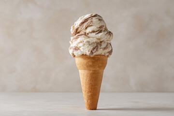 delicious ice cream cone with single piece of bright chocolate on top set against clean neutral background