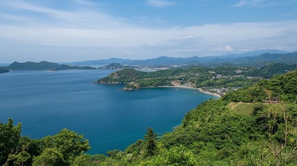 Panoramic coastal view of a serene bay nestled between lush green hills and a distant mountain range under a clear sky