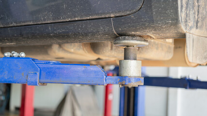 Hydraulic lifting axle machine, using to lift the car for service at automotive garage. Transportation and industrial equipment, close-up with selective focus.