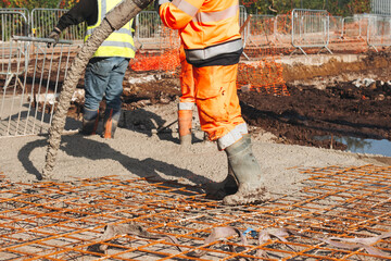 Construction worker pouring concrete onto reinforcing mesh at a building site