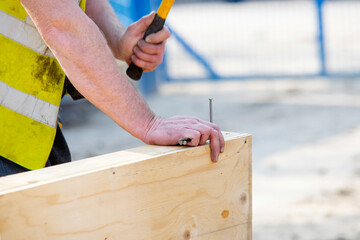 Close-up of hands of builder joiner using plywood and timber to asseble shutter panel for concrete...