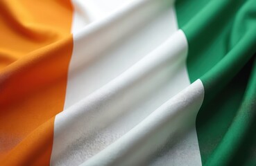 Close-up photo of the Irish flag. This tricolour, a symbol of national identity, features green white orange stripes, fluttering with cloth texture. This photo is perfect for showcasing pride.