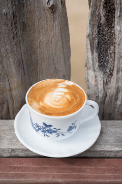 Flat white coffee in a vintage teacup in a rustic setting