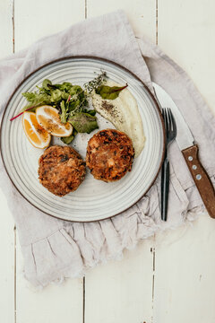 Fish cakes on a plate with lemon and salad