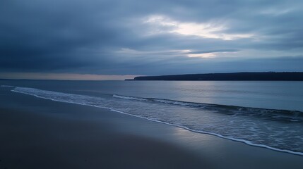 Obraz premium Serene coastal scene at twilight, gentle waves lapping the shore under a brooding sky, distant landmass visible