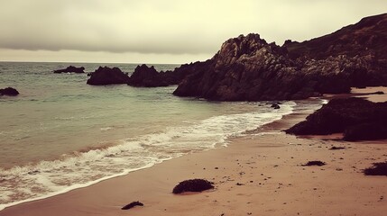 Serene coastal scene calm waves lap a sandy beach, framed by dark rocks and a brooding sky