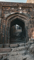 A mysterious, ancient stone archway leads into a dark passage, hinting at the history within a fort...