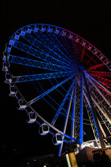Large ferris wheel lit up at night in tricolore for Bastille Day