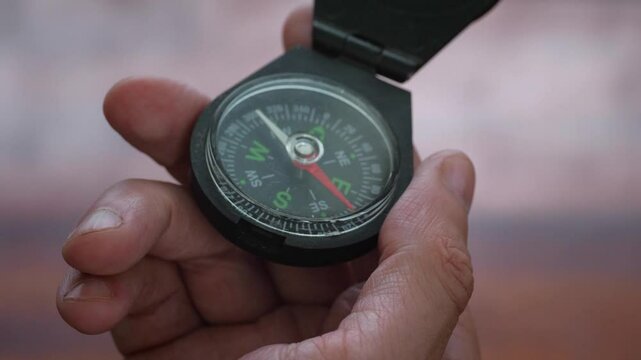 A purposeful and adventurous mood is captured as a hand holds a compass, clearly showing the needle pointing towards North East, suggesting direction, exploration, or decision-making