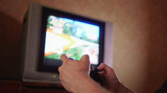 An engaged and immersive mood is captured as hands expertly manipulate a game controller, with the blurred action of a video game visible on an older television screen in the background