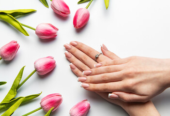 Woman showing french manicure near pink tulips on white background