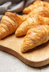 Freshly baked croissants resting on wooden cutting board