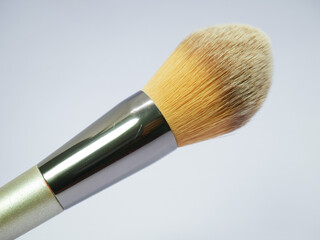 Used foundation brush with golden ferrule on white background