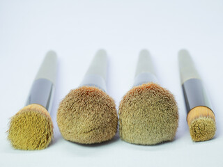 Set of used makeup brushes arranged in a row on white background