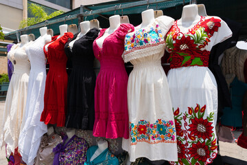 Colorful traditional Mexican dresses on display at an outdoor market in Guadalajara, showcasing vibrant embroidery and regional fashion heritage