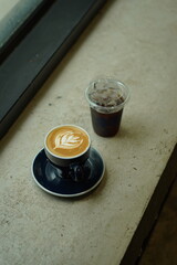 a cup of ice amaricano and latte art on the table