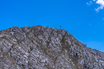 Close view of Hafelekarspitze peak from Hafelekar cable car station on a sunny day in Spring with moon in blue sky, Innsbruck, Tyrol, Austria