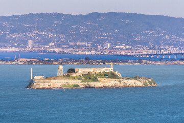 Alcatraz island in San Francisco Bay at sunset showing prison and headlands in the background