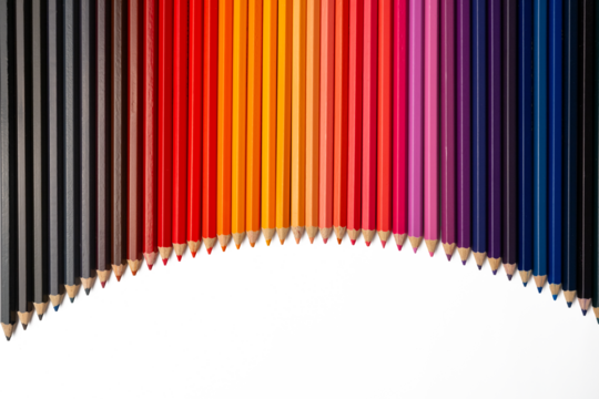 The Photo of colorful colored pencils arranged in a curved line pattern on a white background.
