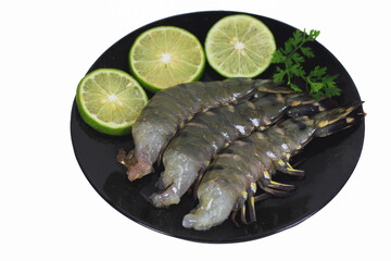 Fresh Black Tiger Shrimp without Heads with Shells on Black Plate with Thin Lime Slices and Thai Coriander on White Background – Clipping Path Included