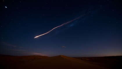 Falling meteor with trail of light in the night sky over desert