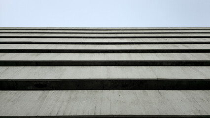 Angle from below of old grey parking building. Old parking building in Bangkok. Parking building from ground floor to upper floor and sky.