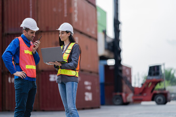 Two logistics workers man and woman discuss operations at a busy shipping container yard. successful coordination in freight, transportation, and supply chain operations