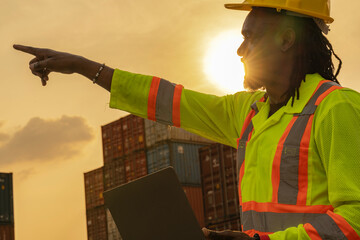 African logistics workers man cheking on site area operations at a busy shipping container yard at...