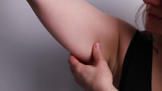 slow motion close up of girl troubled by excess arm fat in her room