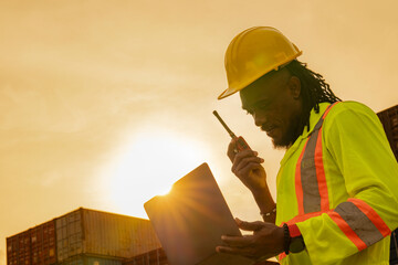 African logistics workers man cheking on site area operations at a busy shipping container yard at...